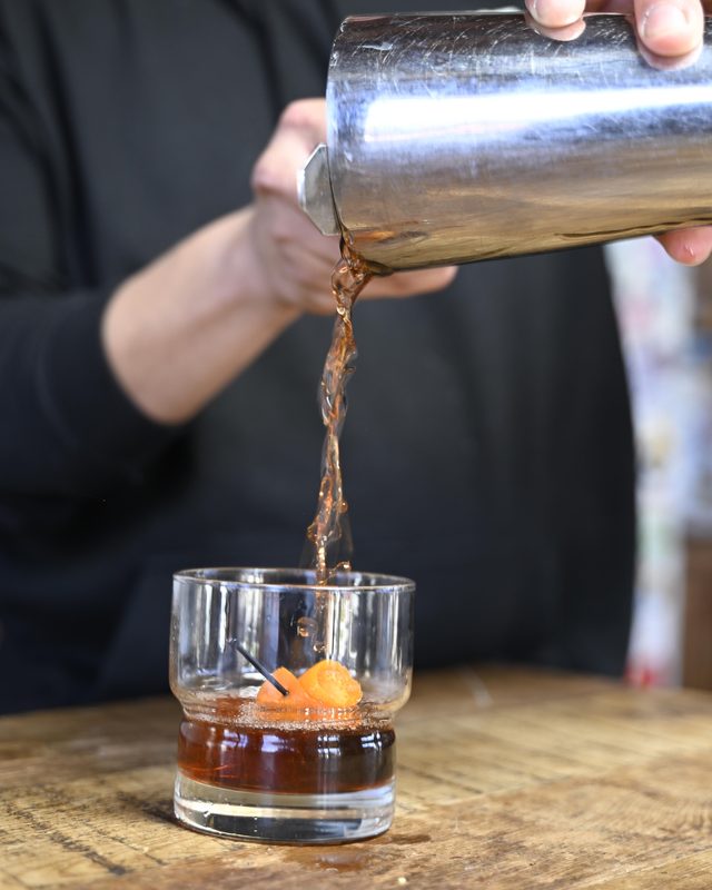 Bartender pouring a cocktail over ice