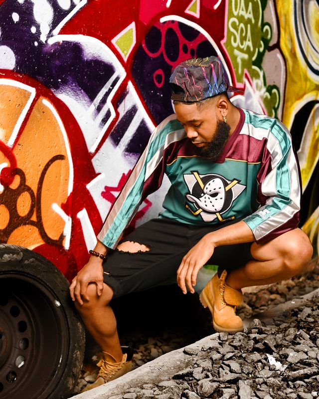 Justin Riley in a menswear look against street graffiti