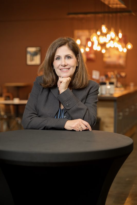 Ann Barham of Transworld Business Advisors at a cocktail table, on-location portrait