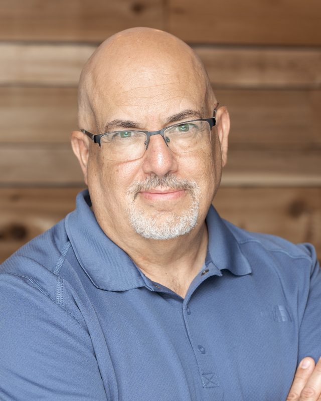 Rico Figliolini of Mighty Rockets, headshot on a wood backdrop